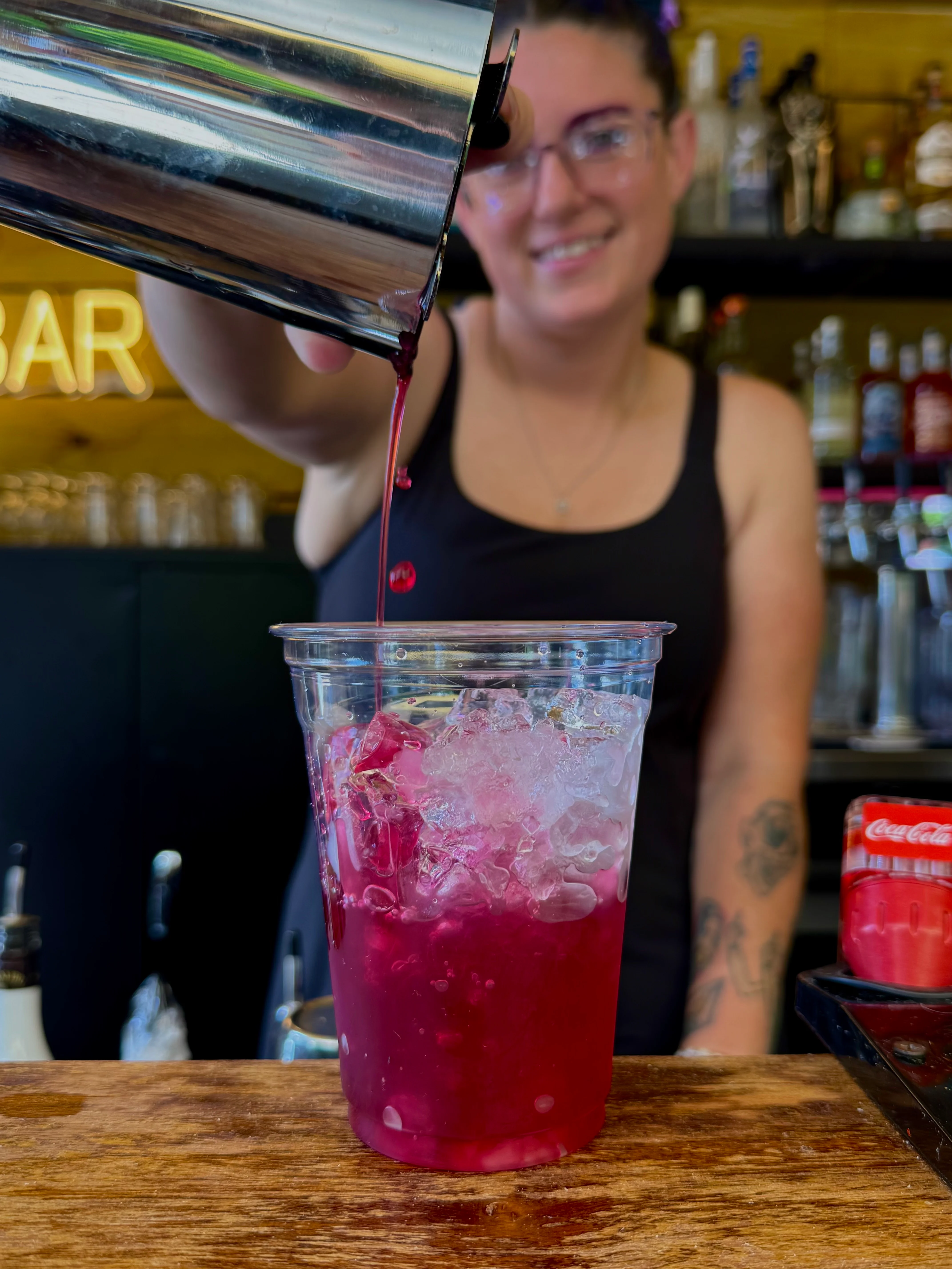 Bartender pouring a vibrant cocktail at a lively bar