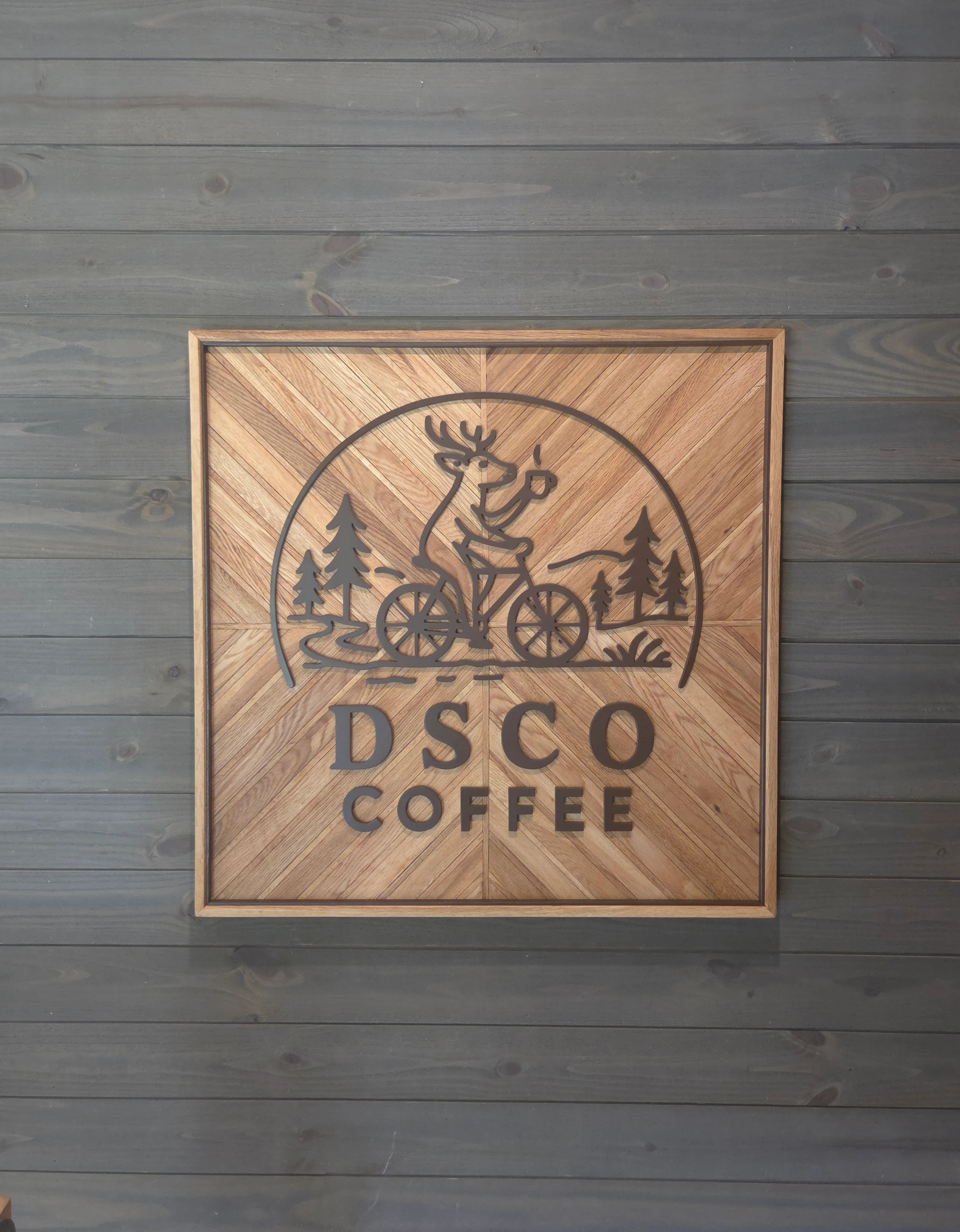Stylish wooden coffee shop logo with a deer on a bicycle