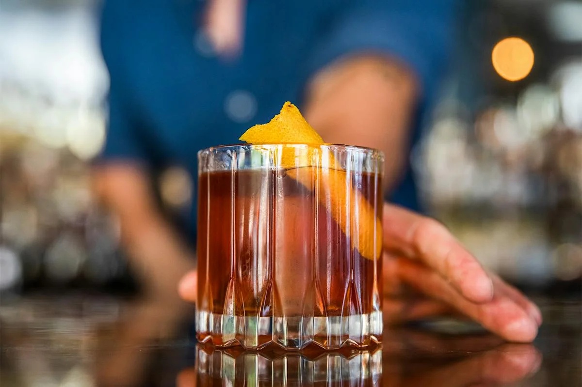 Classic Old Fashioned cocktail with orange twist at a bar