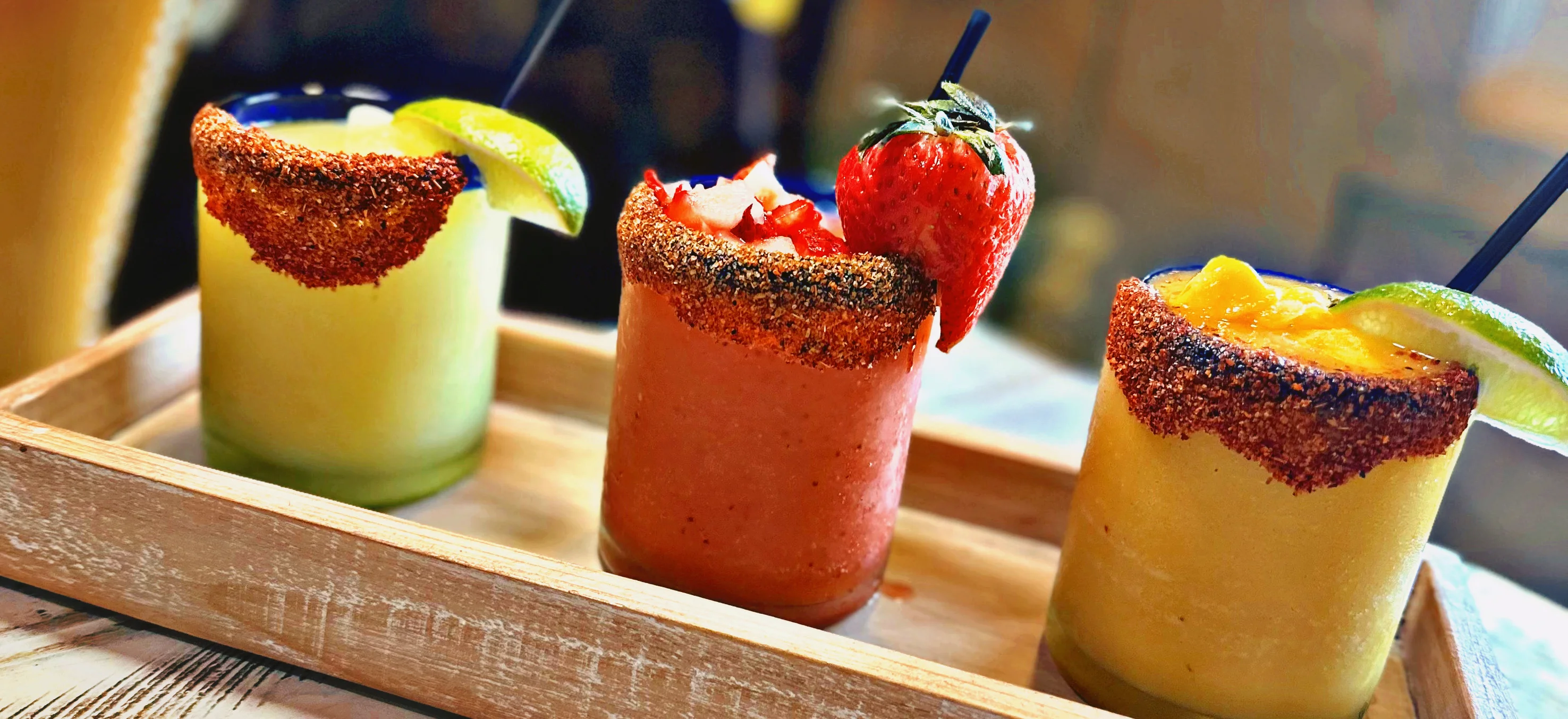 Colorful margaritas served in a wooden tray