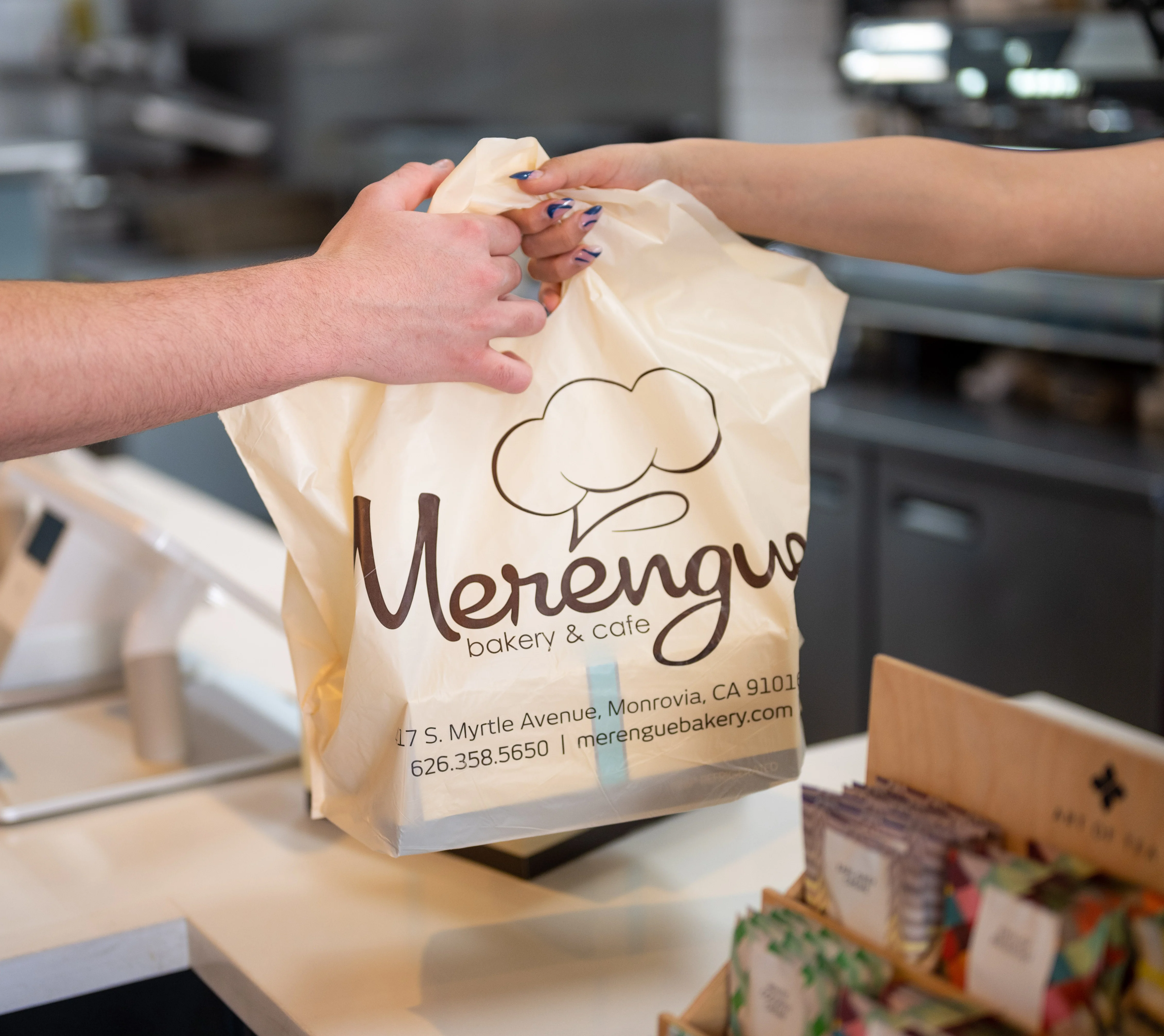Customer receiving a bakery bag at Merengue Bakery & Cafe