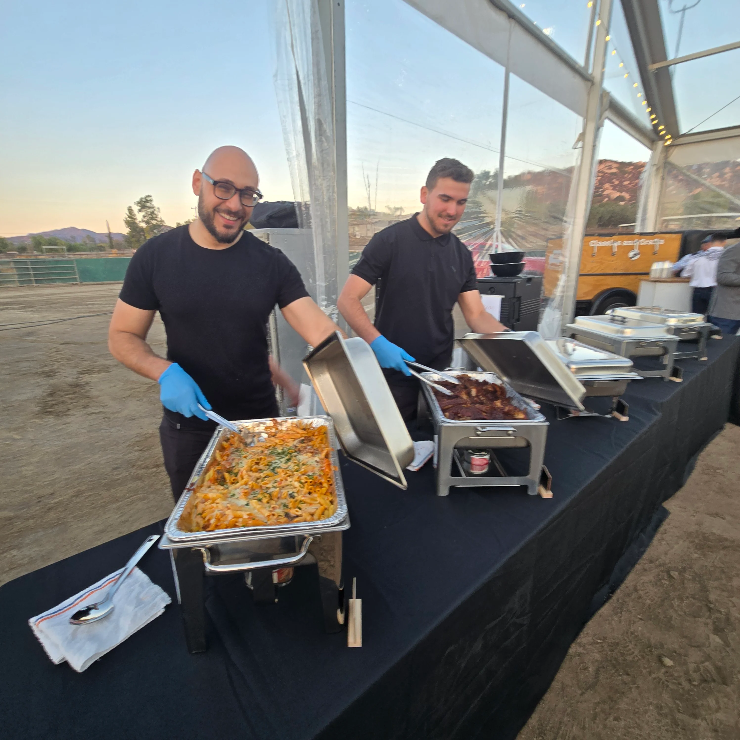 Catering service with pasta and grilled meats at an outdoor event