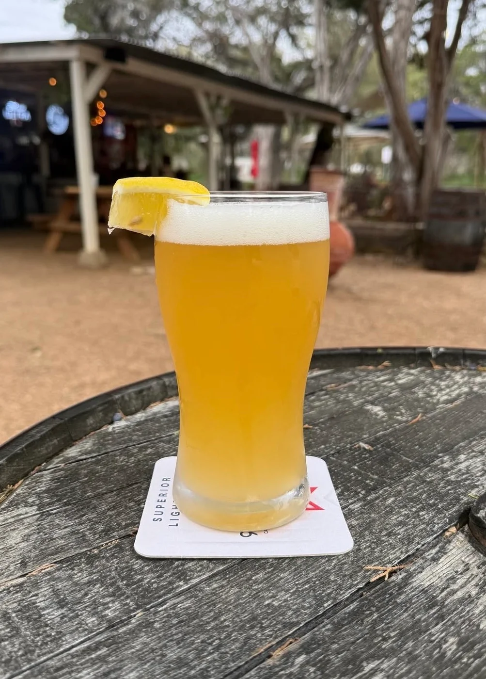 Refreshing glass of beer with lemon slice on a rustic wooden table