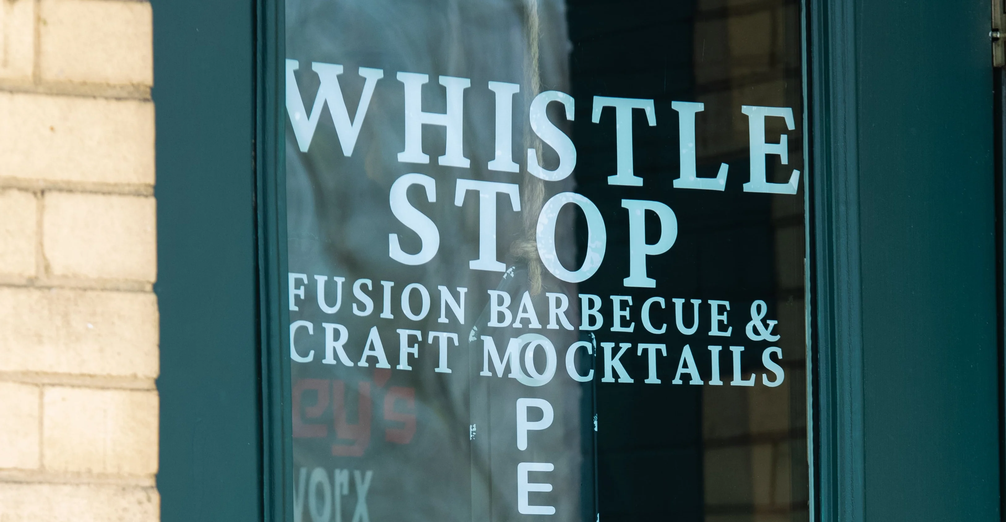 Entrance of Whistle Stop barbecue restaurant with hours displayed
