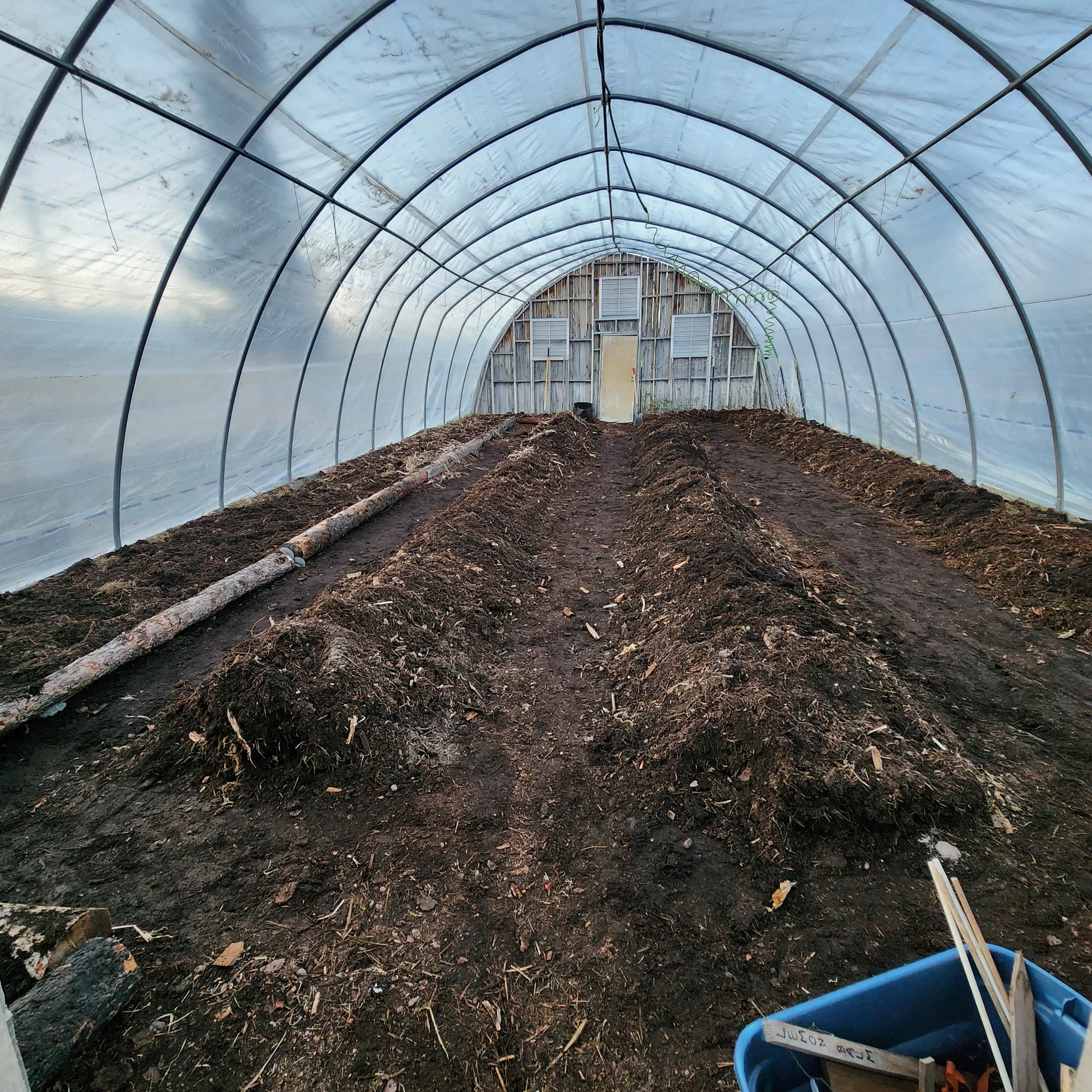 Interior of a greenhouse with soil beds and wooden structure