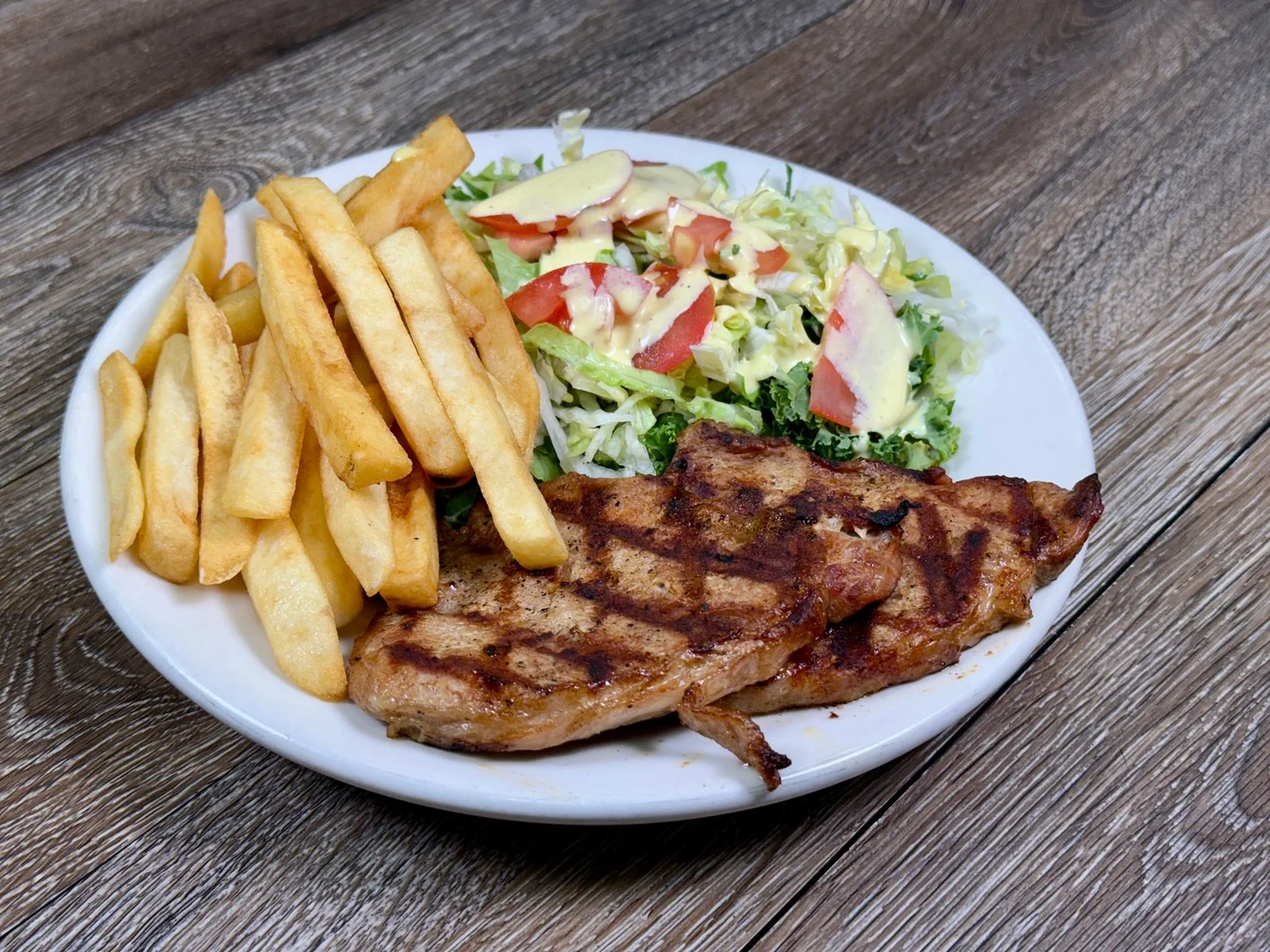 Grilled pork chop with fries and salad