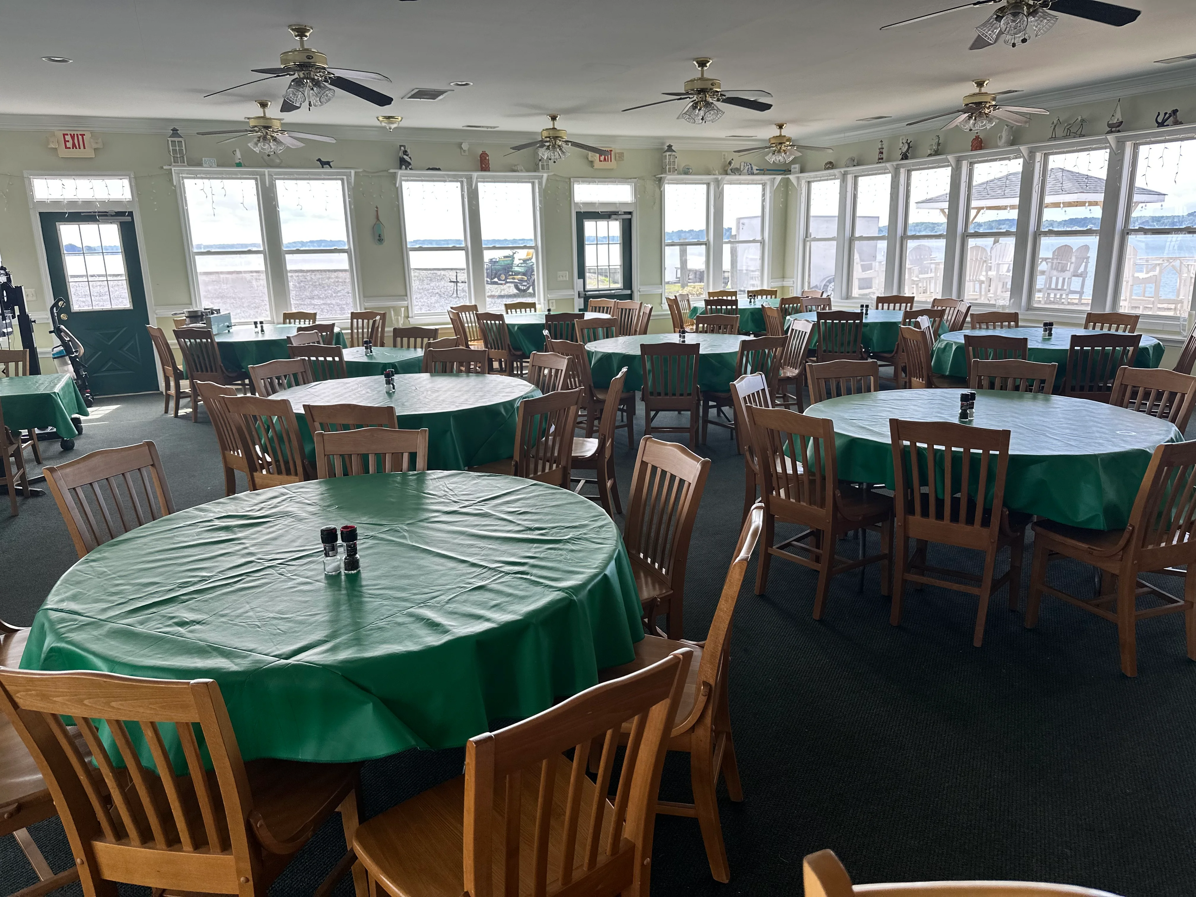 Dining area with green tablecloths and wooden chairs, overlooking a scenic view.
