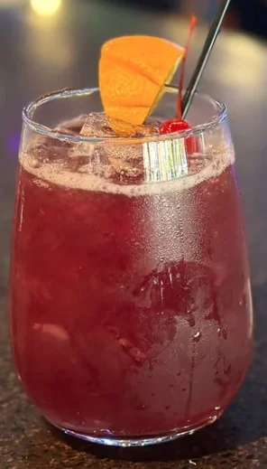 A refreshing glass of red sangria with fruit garnishes.