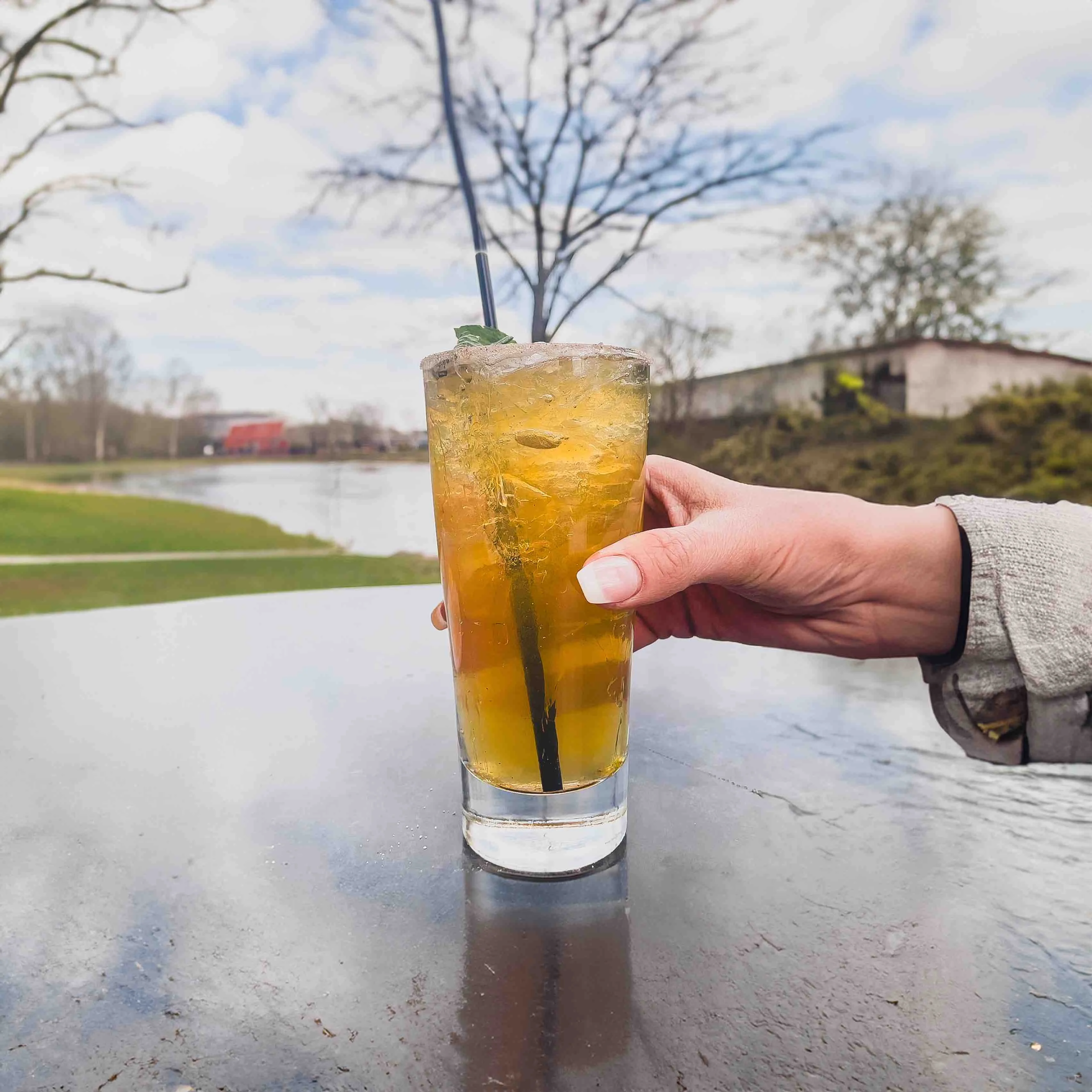 Peach Julep cocktail on a table outside on the patio by the river