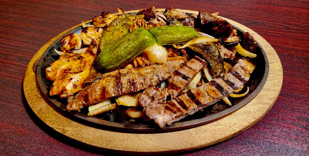 Sizzling mixed grill platter with meats and vegetables
