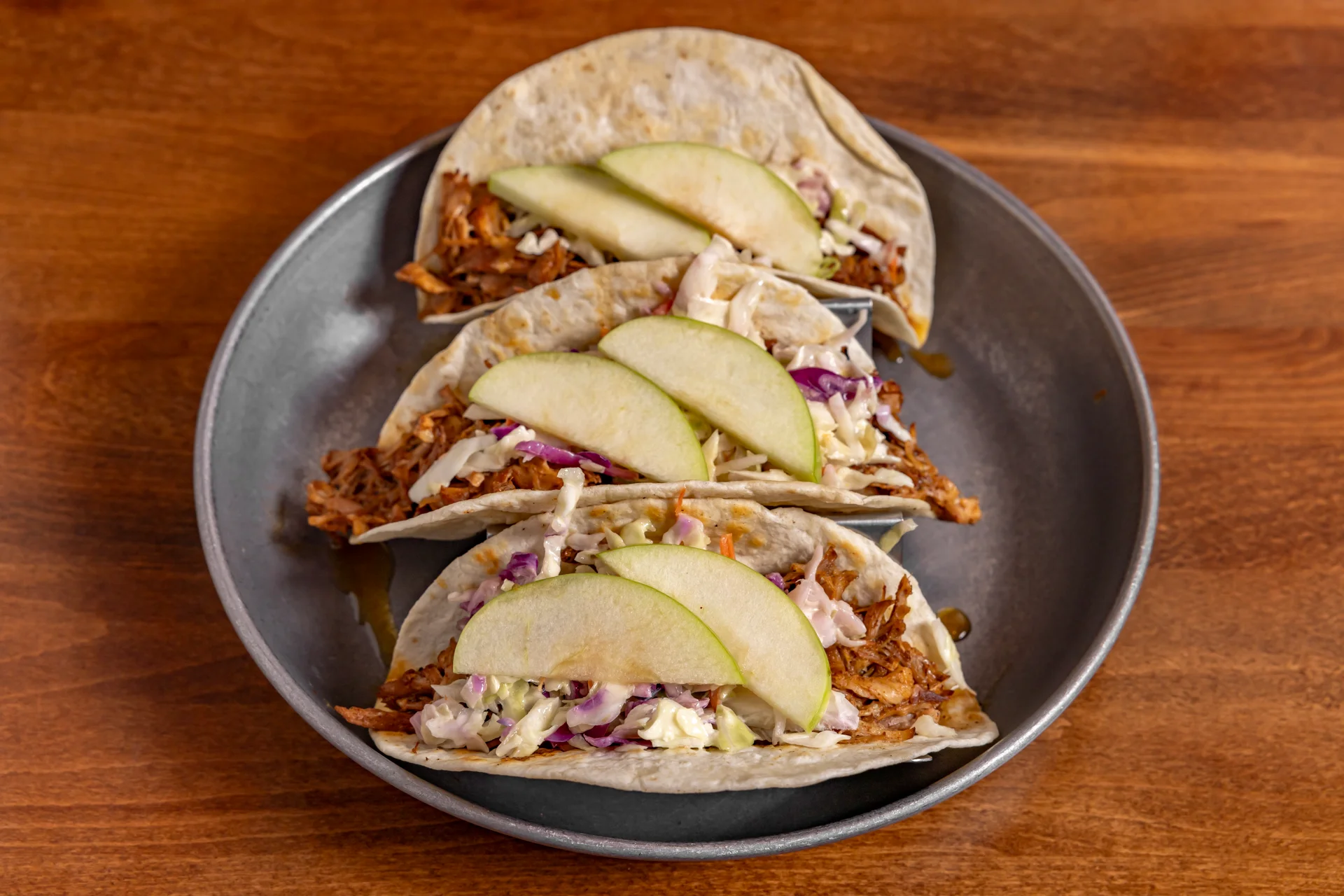 Three delicious chicken tacos with apple slices