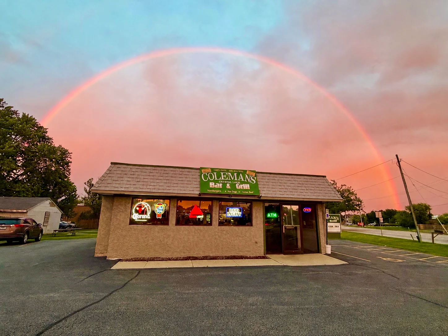 Charming restaurant exterior under a vibrant rainbow at sunset
