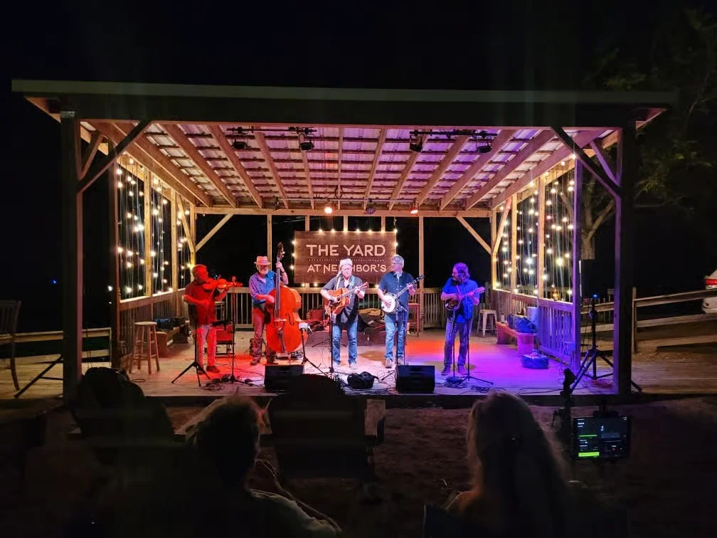 Live music performance at a rustic outdoor venue with string lights