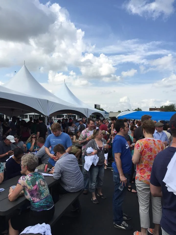 Crowd enjoying an outdoor food festival under large tents