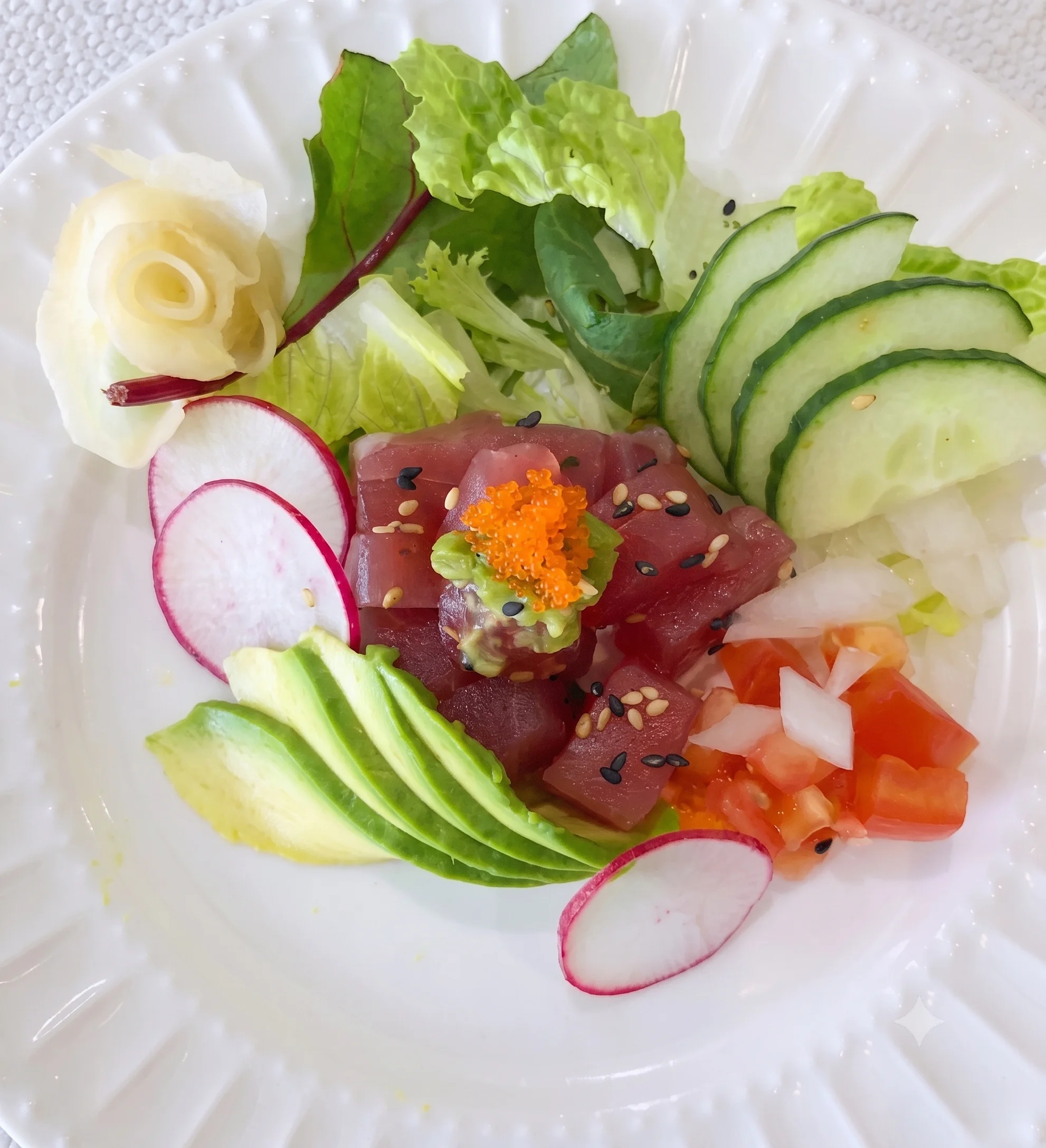 A colorful sashimi platter with fresh tuna, avocado, and assorted vegetables.