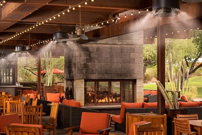 Cozy outdoor restaurant patio with misting fans and a fireplace