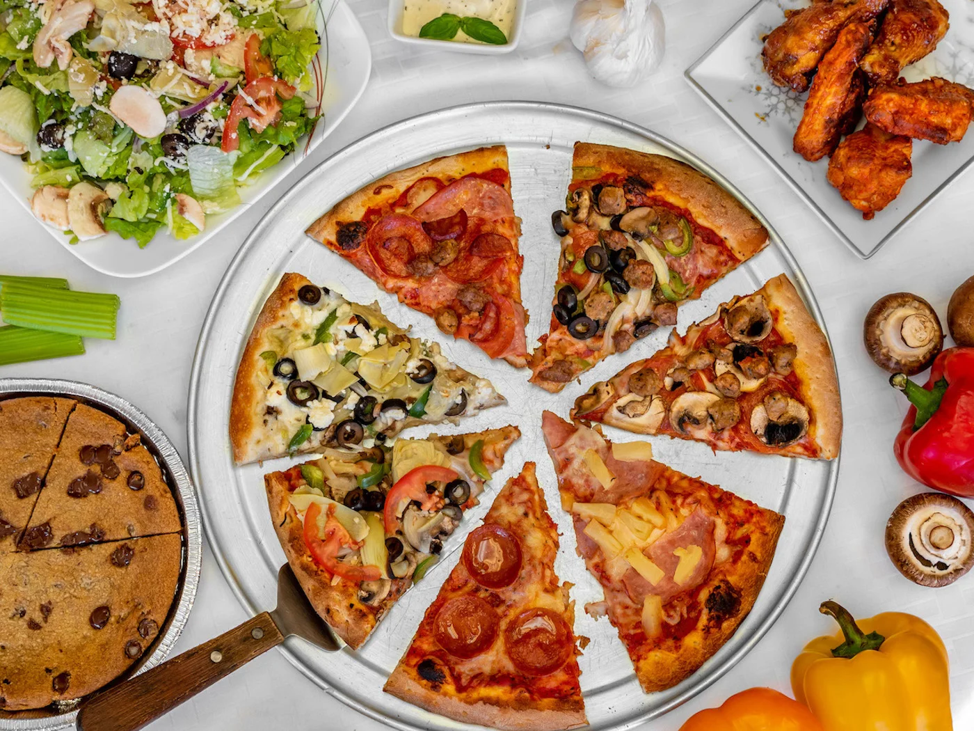 Variety of pizzas on a silver platter with sides and salad