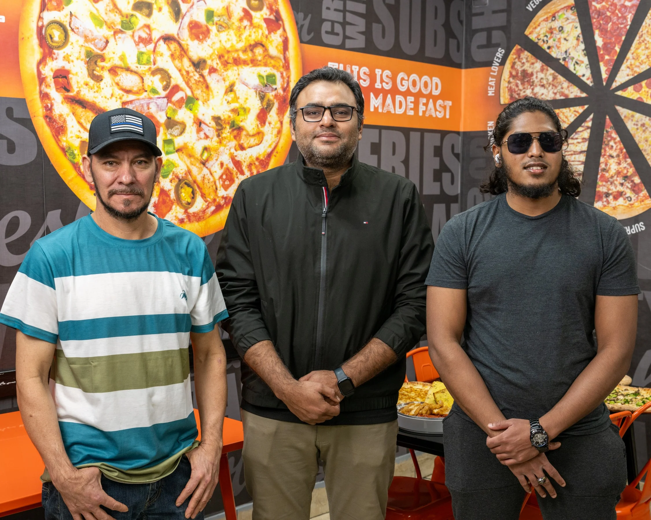 Restaurant staff posing in front of a pizza display