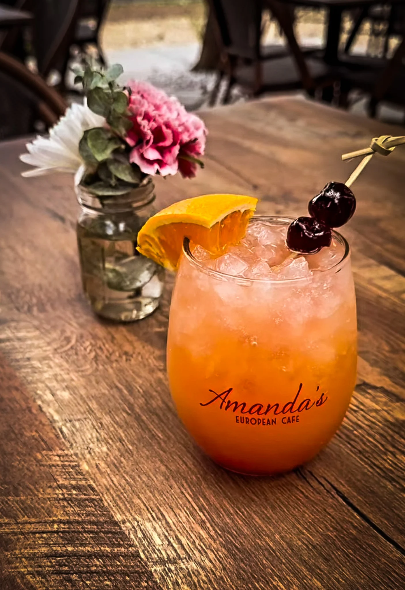 Colorful cocktail with orange slice and cherries at a cafe table