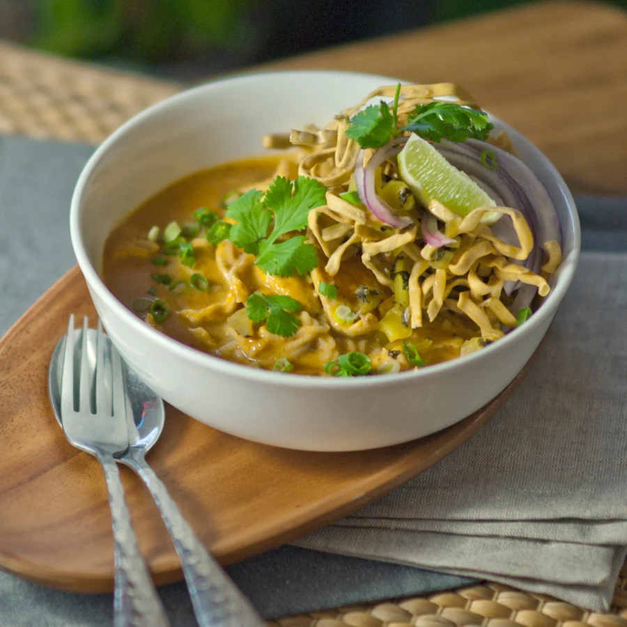 Bowl of Burmese Khao Soi with crispy noodles and fresh herbs