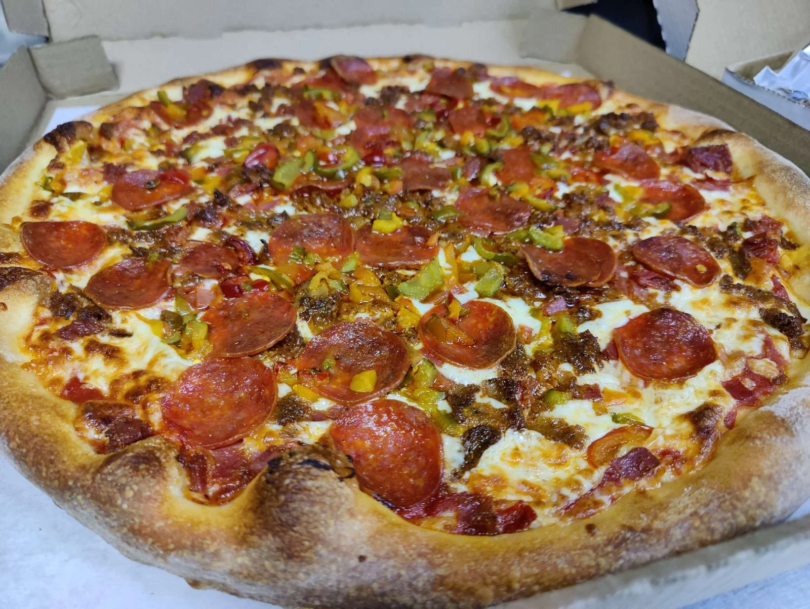 A beautifully decorated meat lovers pizza