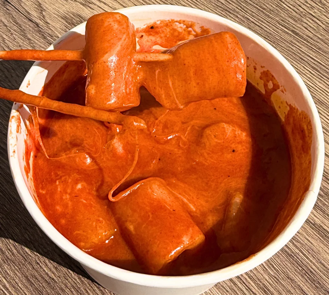 Bowl of spicy red sauce with marshmallows and chopsticks