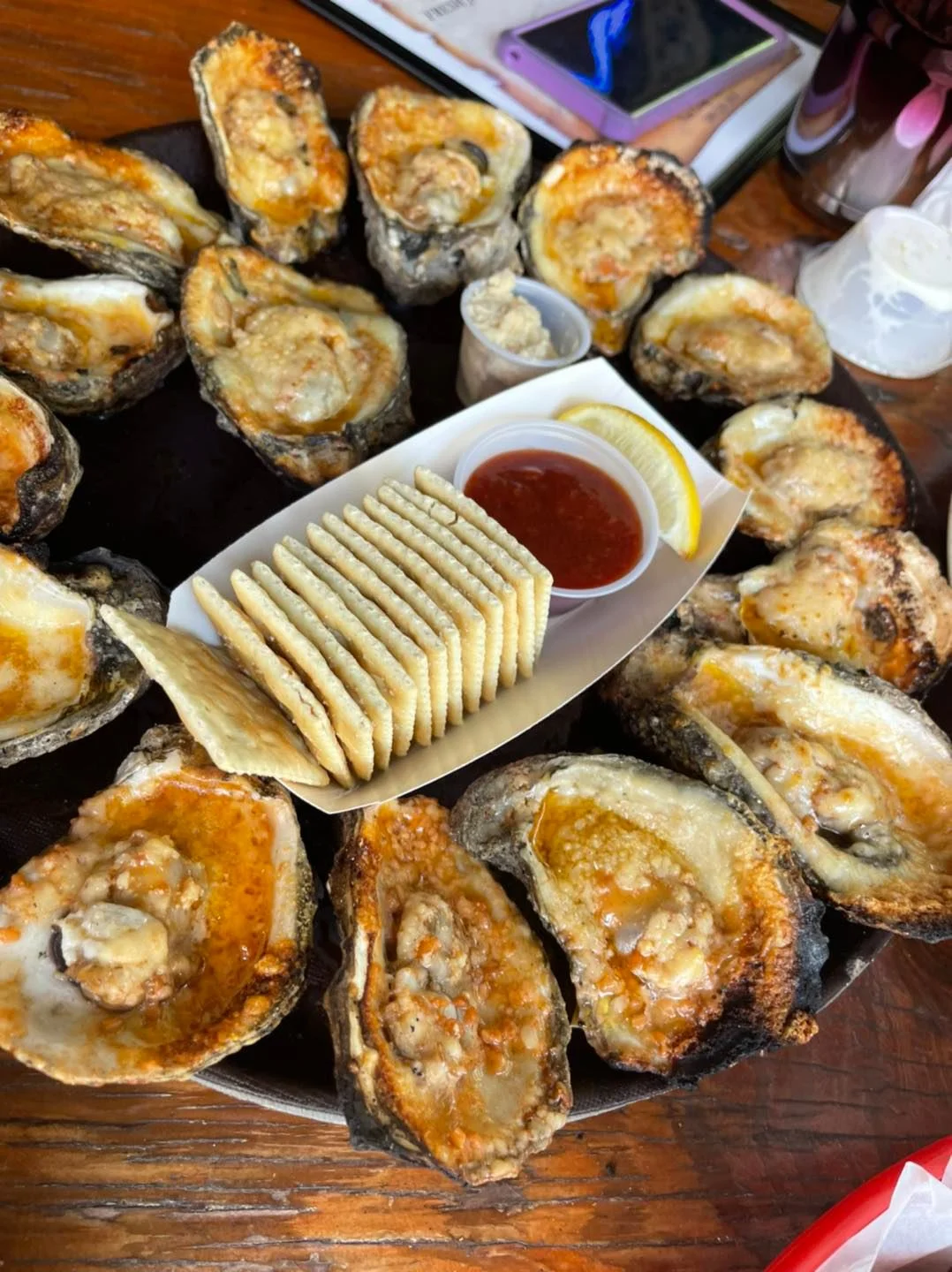 Baked oysters on a platter with crackers and dipping sauce