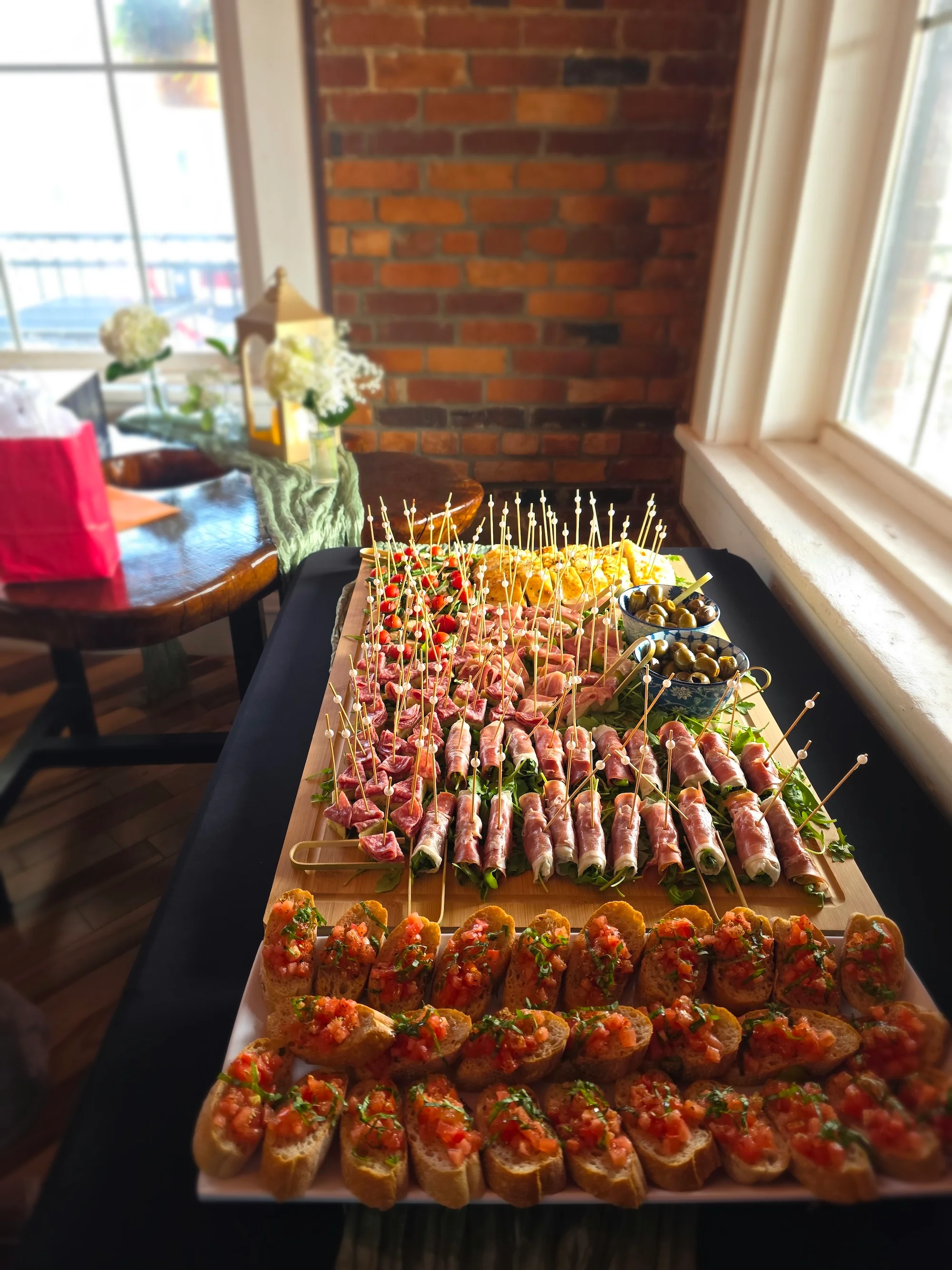 An elegant spread of appetizers arranged on a platter, featuring various wrapped items, bruschetta, and garnished with decorative toothpicks.