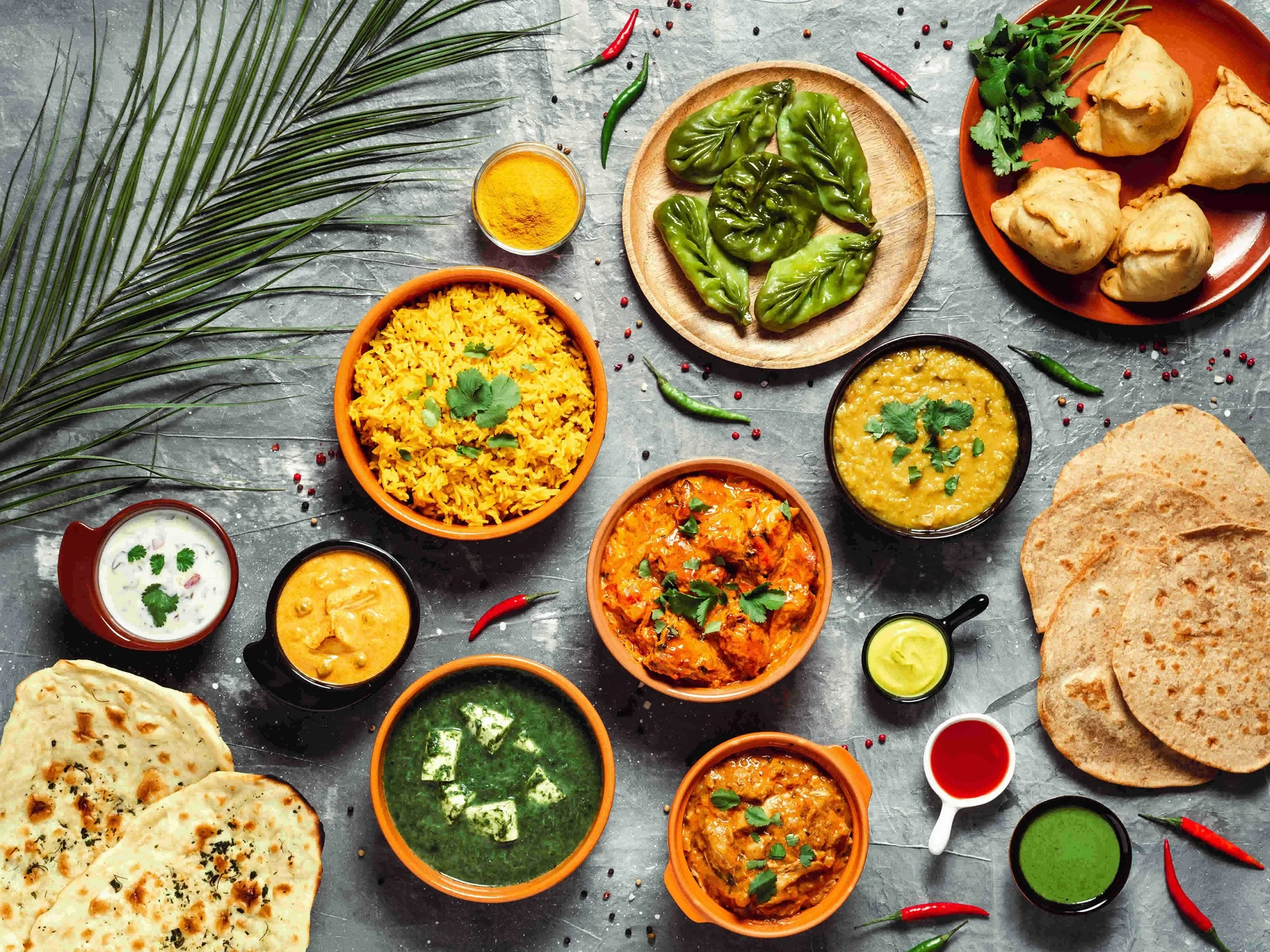 A buffet spread featuring a variety of dishes, including colorful curries and side items, with one plate loaded with assorted foods.