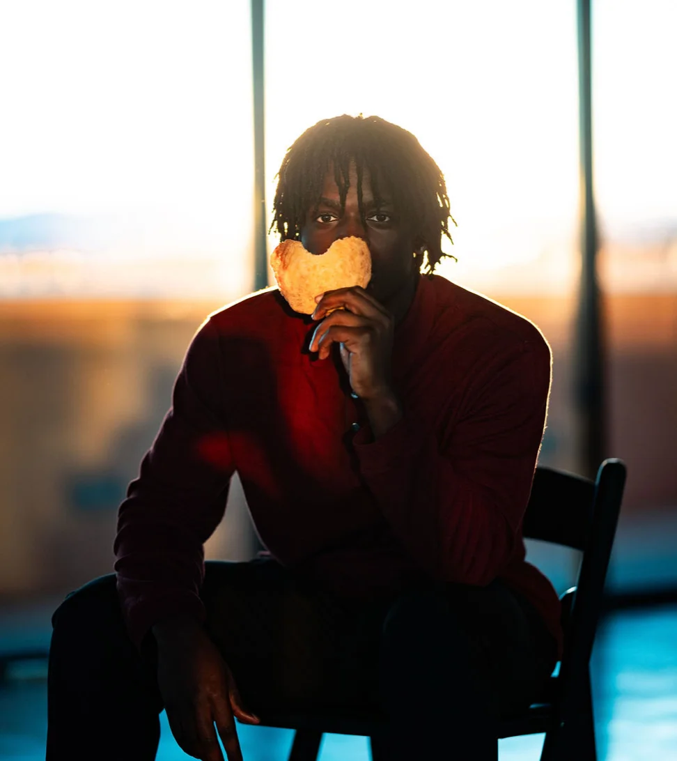 Person holding a large piece of bread against a sunset backdrop
