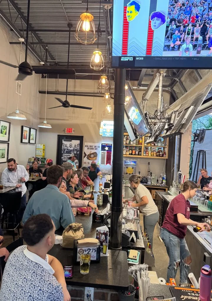 Busy bar scene with patrons enjoying drinks and watching sports on TV