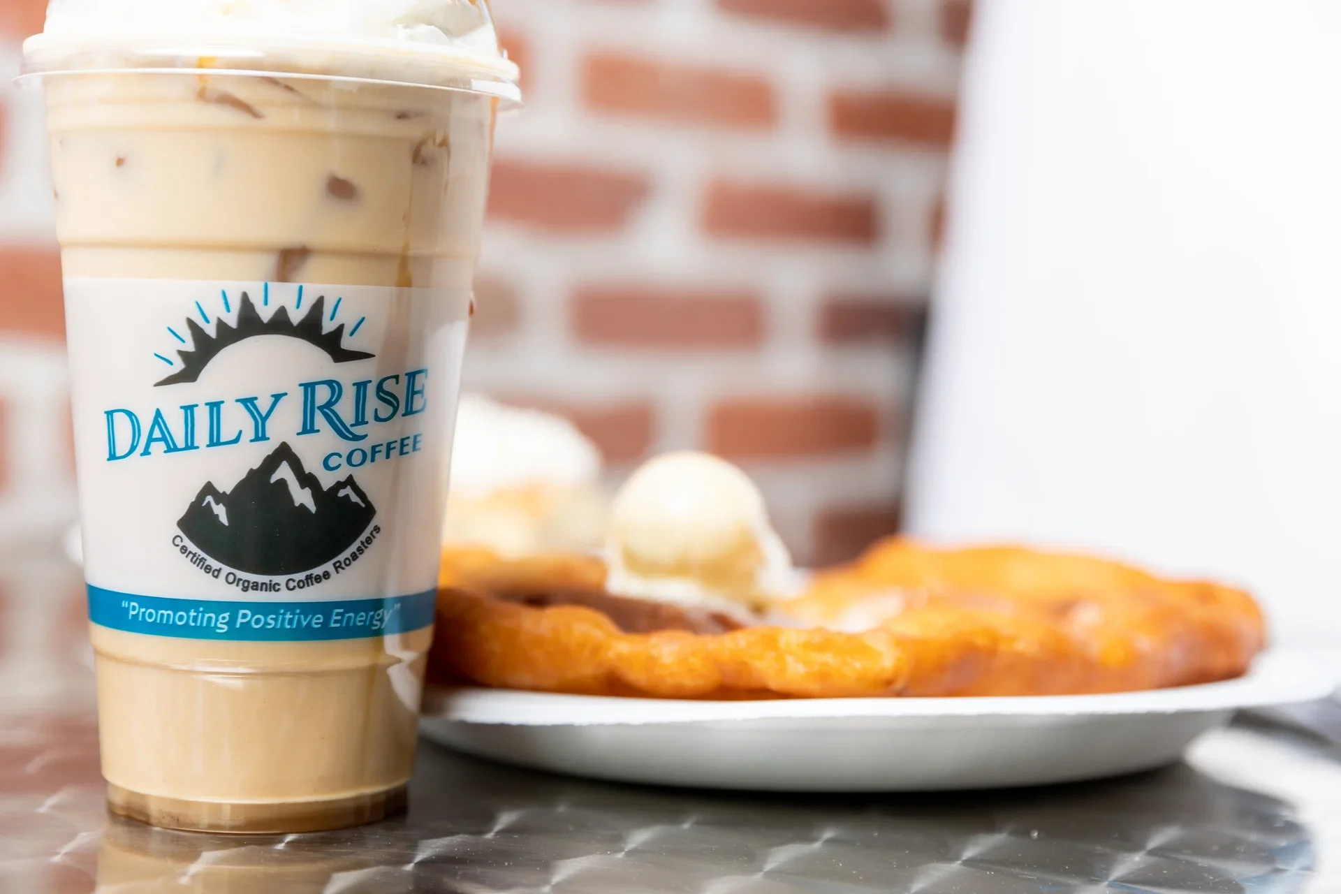 Iced coffee from Daily Rise Coffee with a dessert plate in the background