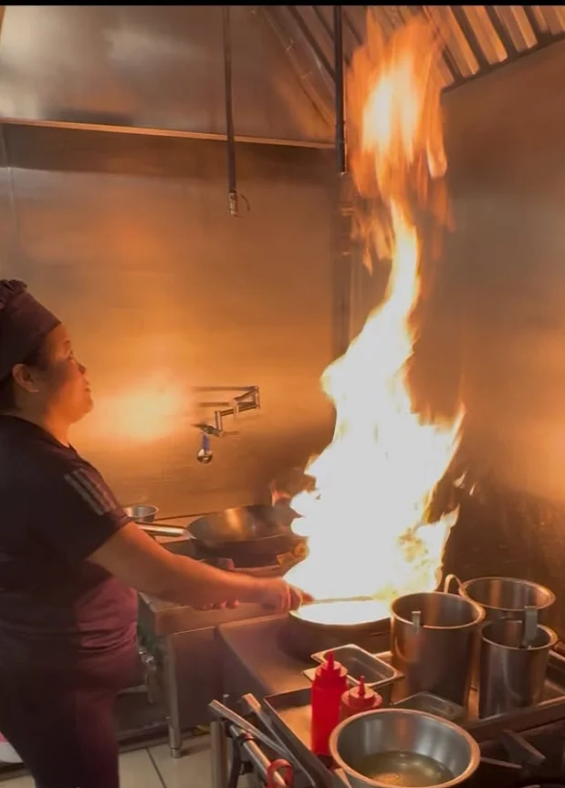 Chef creating a dramatic flame in a busy restaurant kitchen