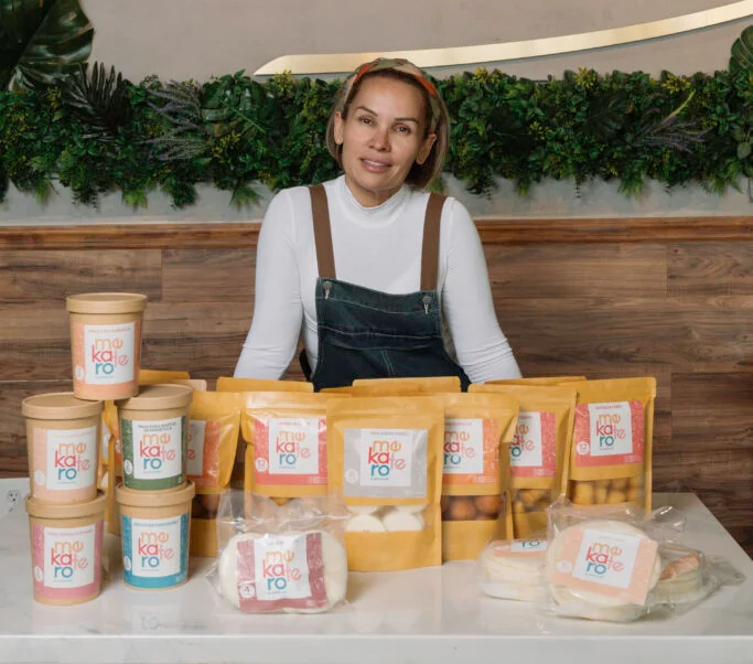 Owner showcasing products at Aroma Cafe with vibrant branding and packaging