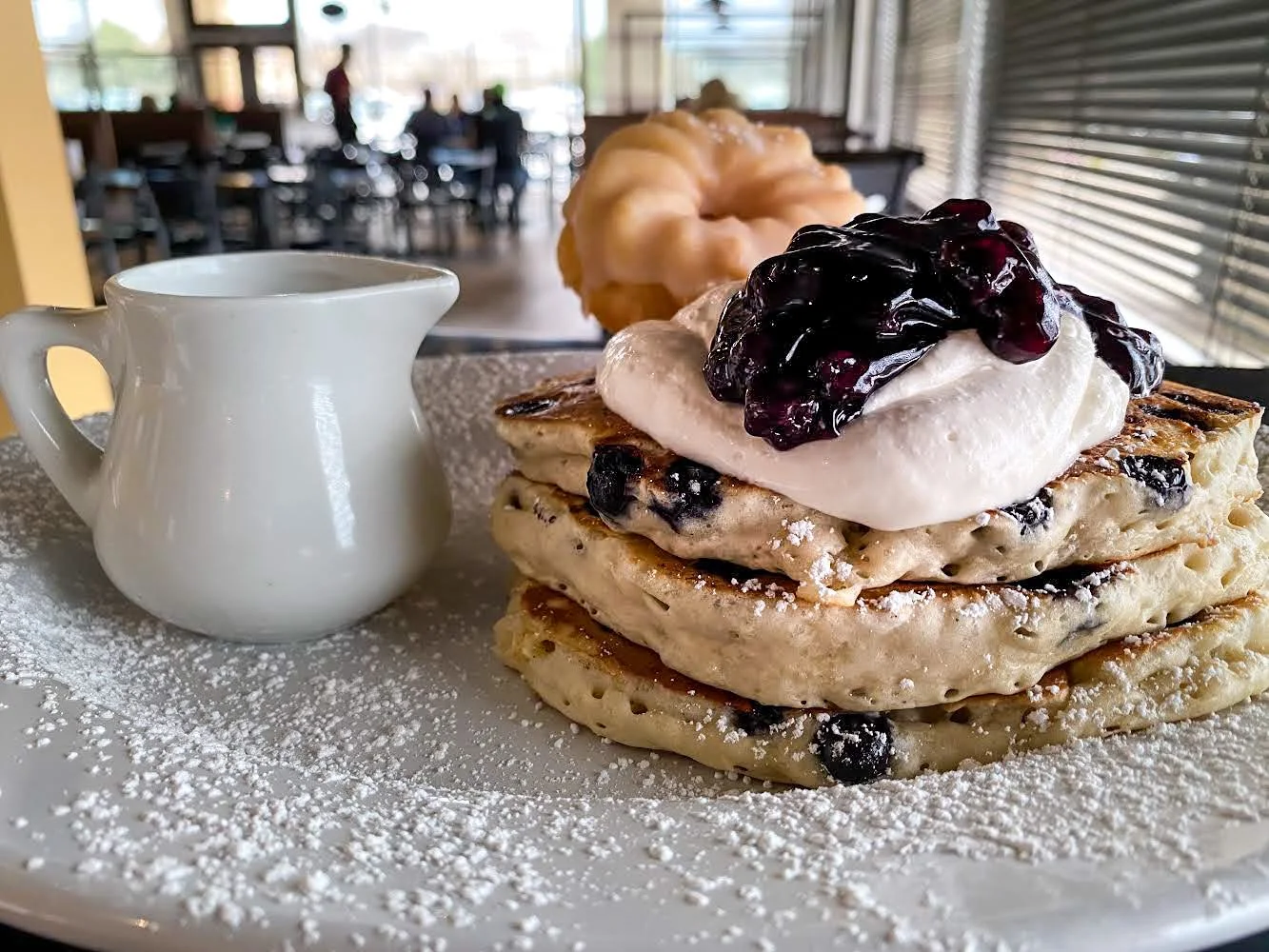Fluffy blueberry pancakes with whipped cream and syrup