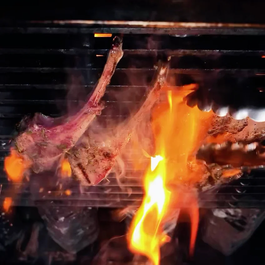 Grilled lamb chops with flames on a barbecue