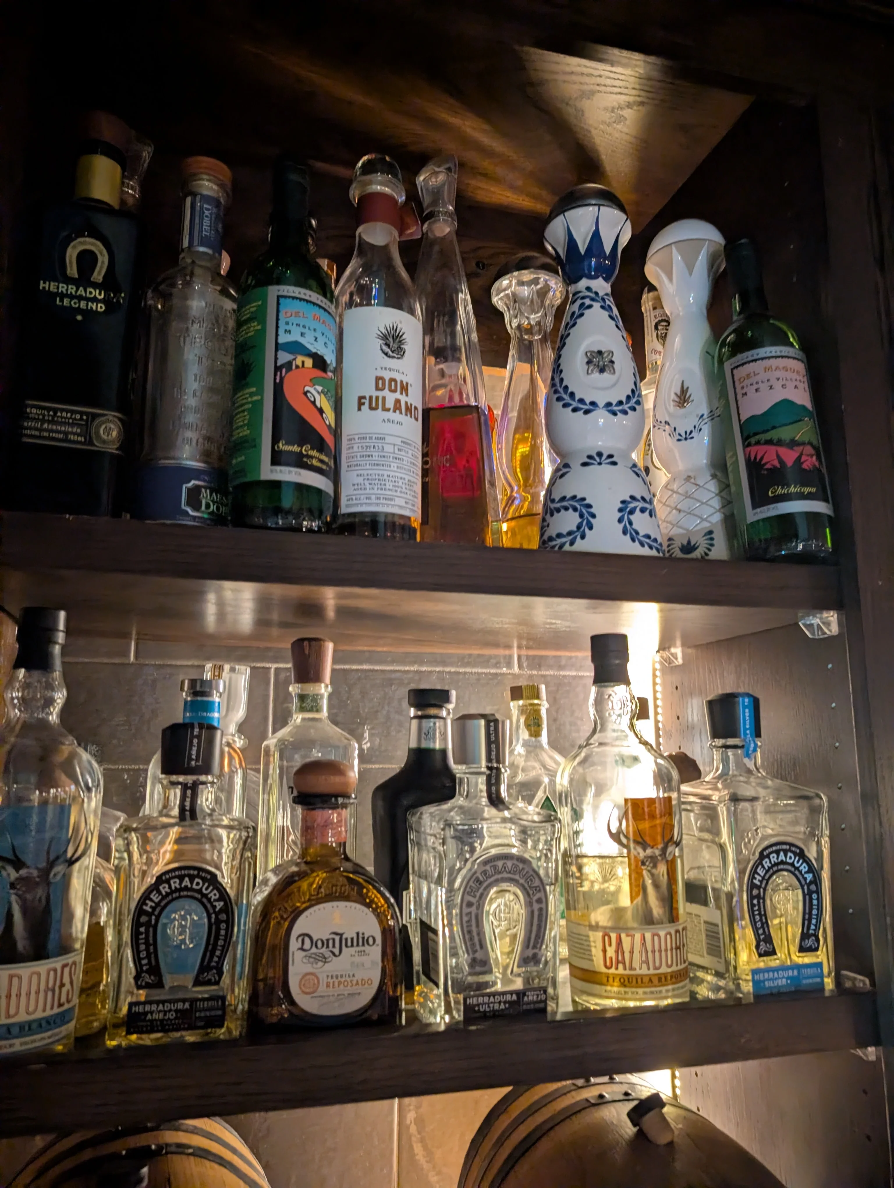 Collection of premium tequila bottles on a wooden shelf
