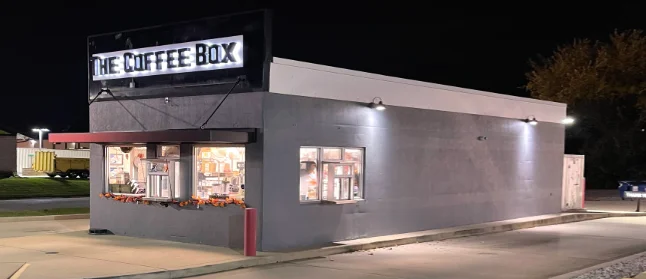Exterior view of The Coffee Box at night with illuminated sign