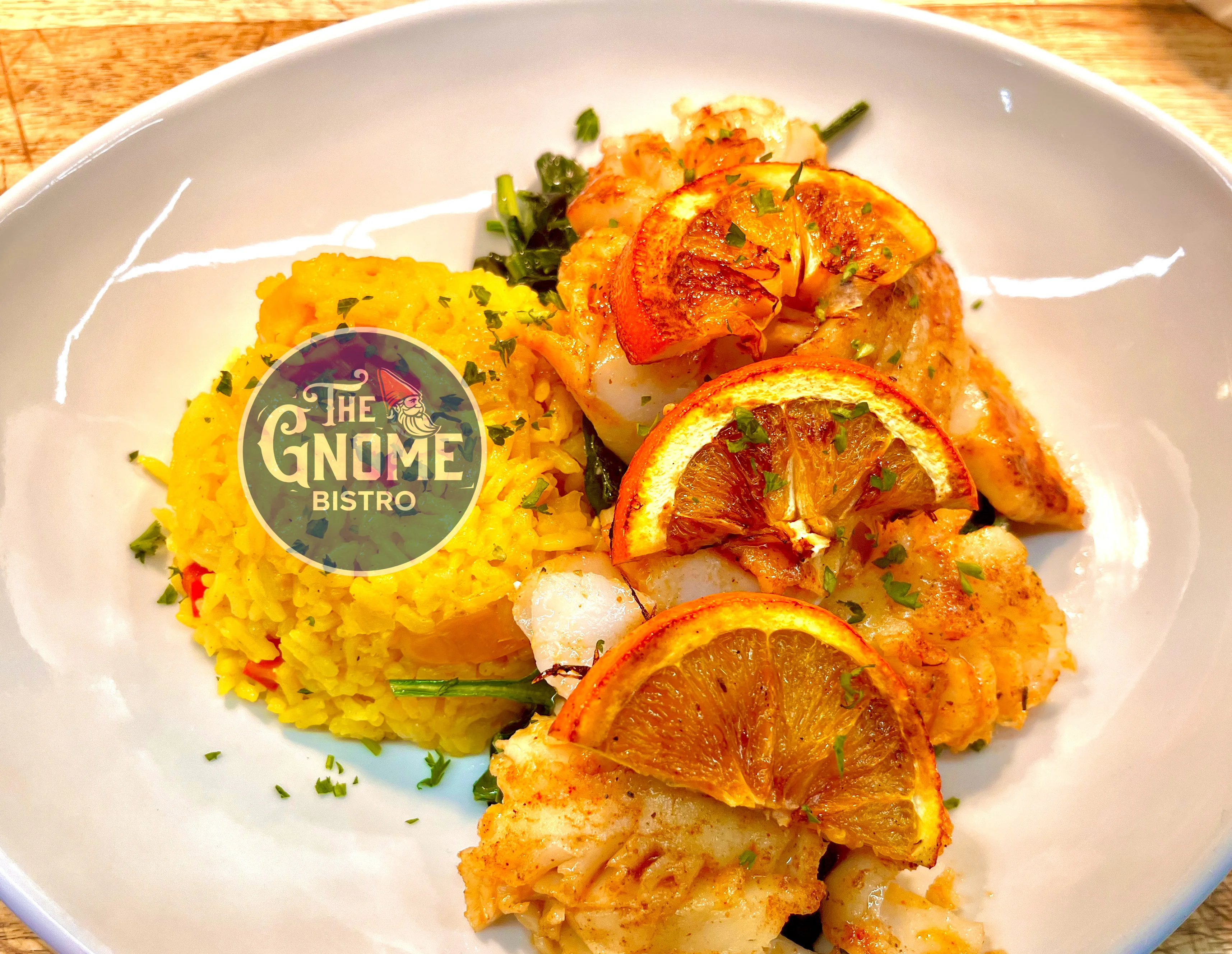 A plate of seafood served with saffron rice and garnished with orange slices, showcasing a colorful and appetizing dish.