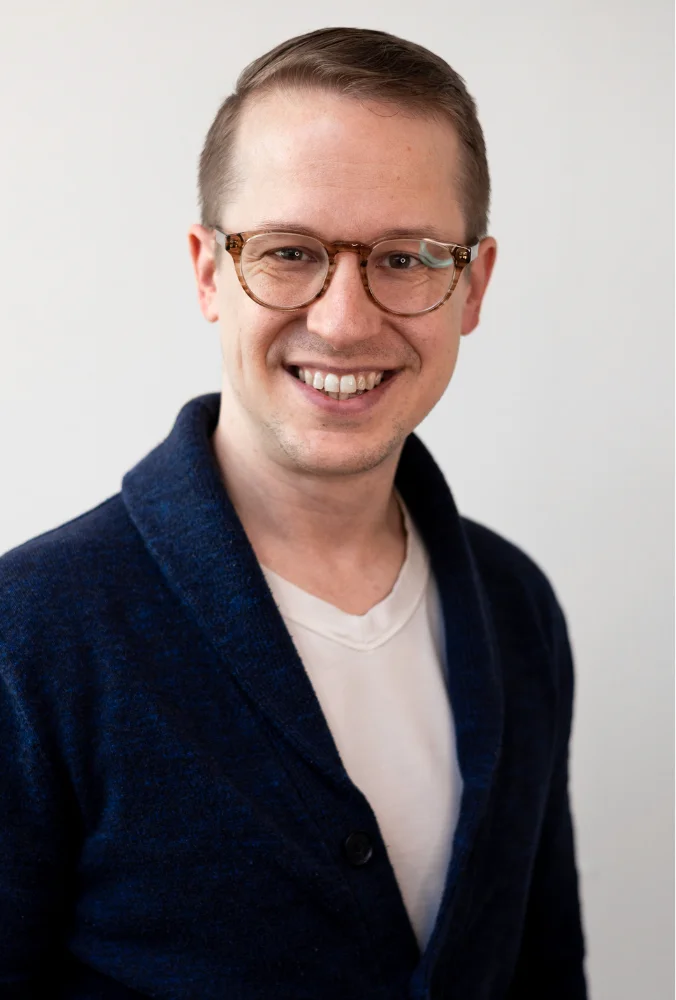 Smiling man in a navy cardigan against a light background