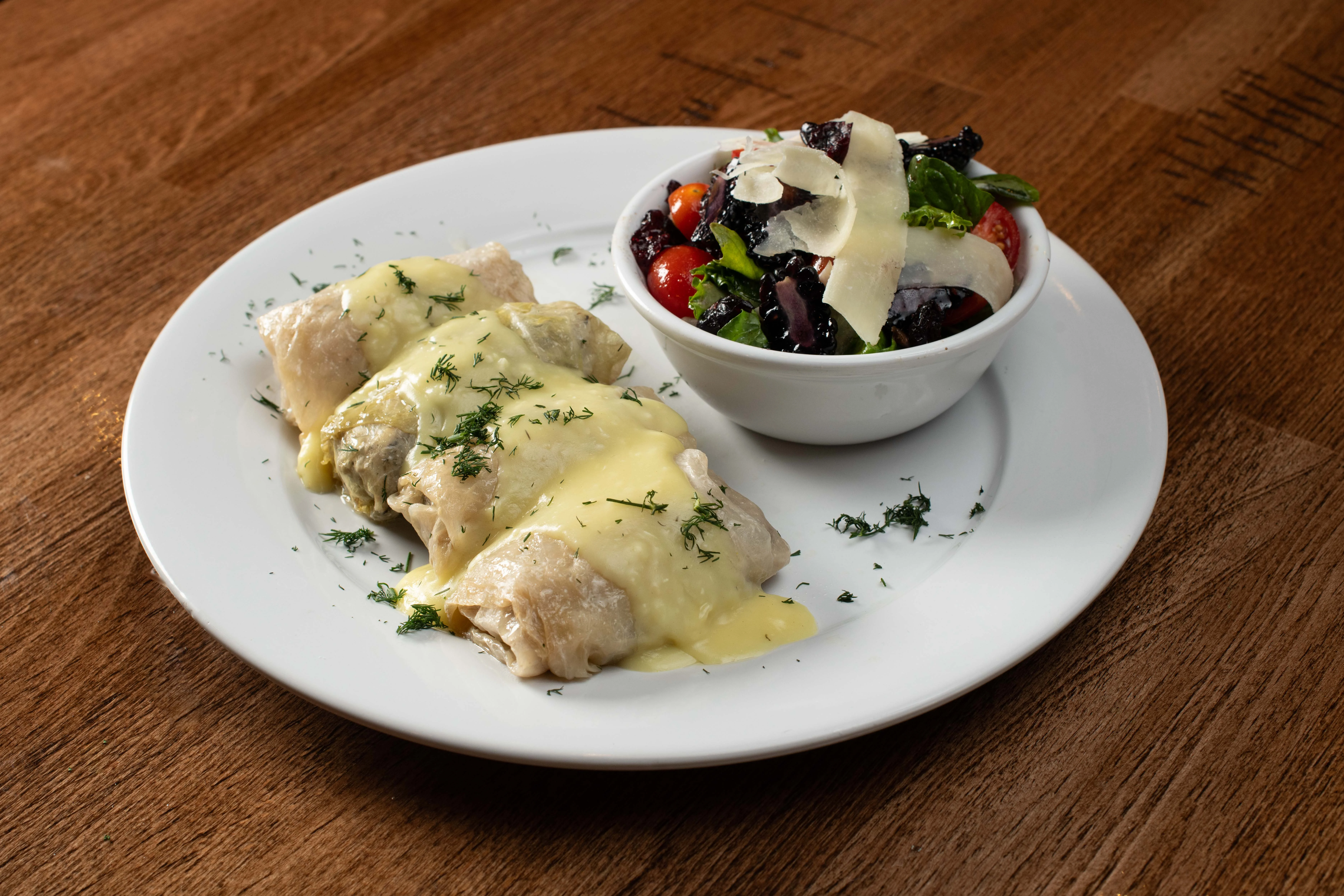 Enchiladas topped with cheese sauce and a fresh garden salad