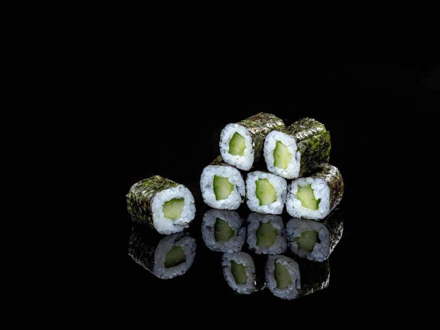 Japanese cucumber sushi rolls on a reflective surface