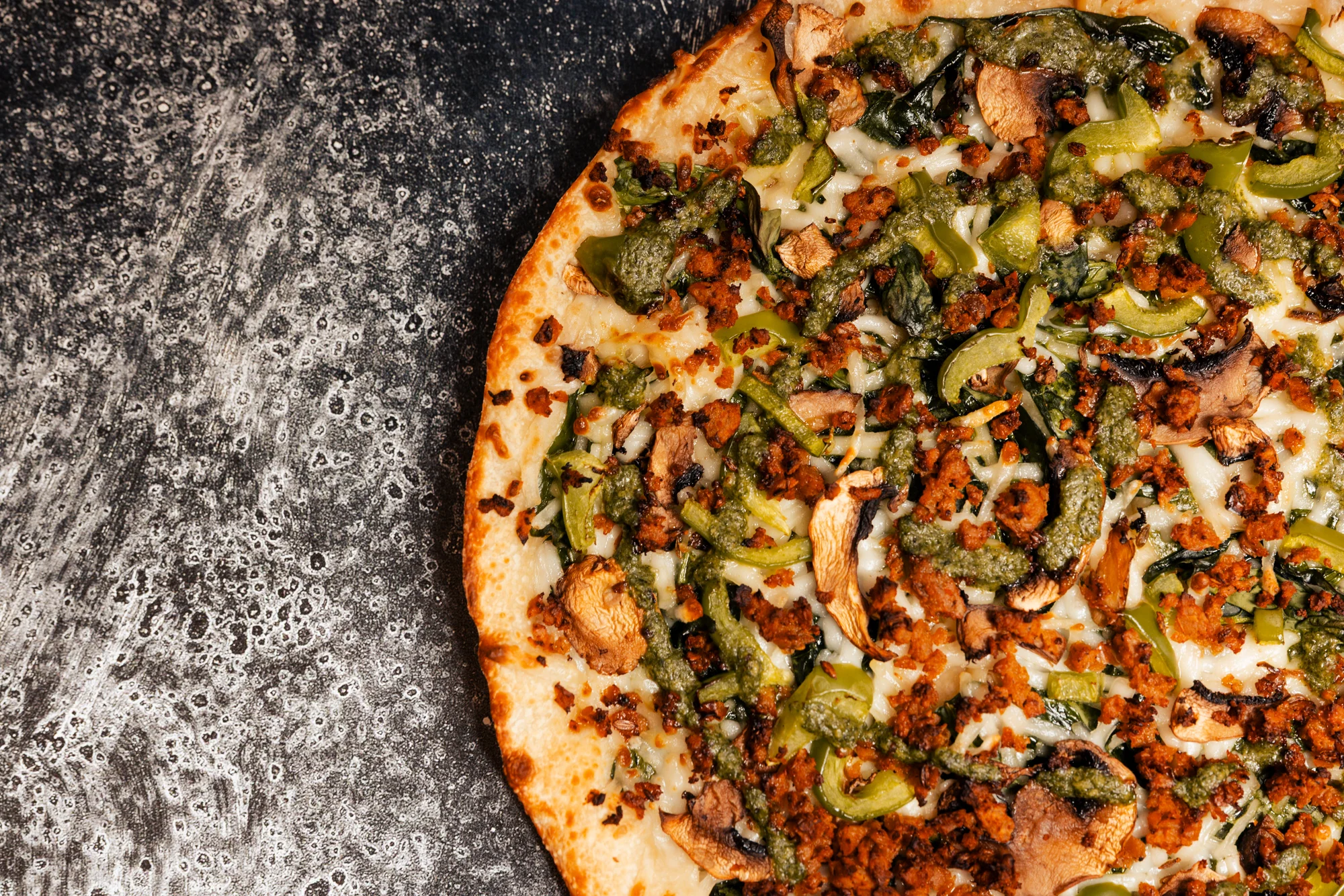 Gourmet Italian pizza with mushrooms, peppers, greens, pesto, and melted cheese