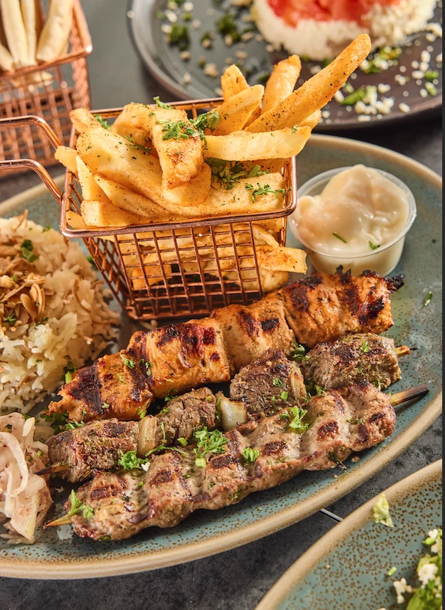 Middle Eastern mixed grill platter with kofta, chicken skewers and fries