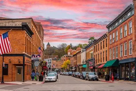 A lively street scene with historic buildings, storefronts, and colorful sunset skies.