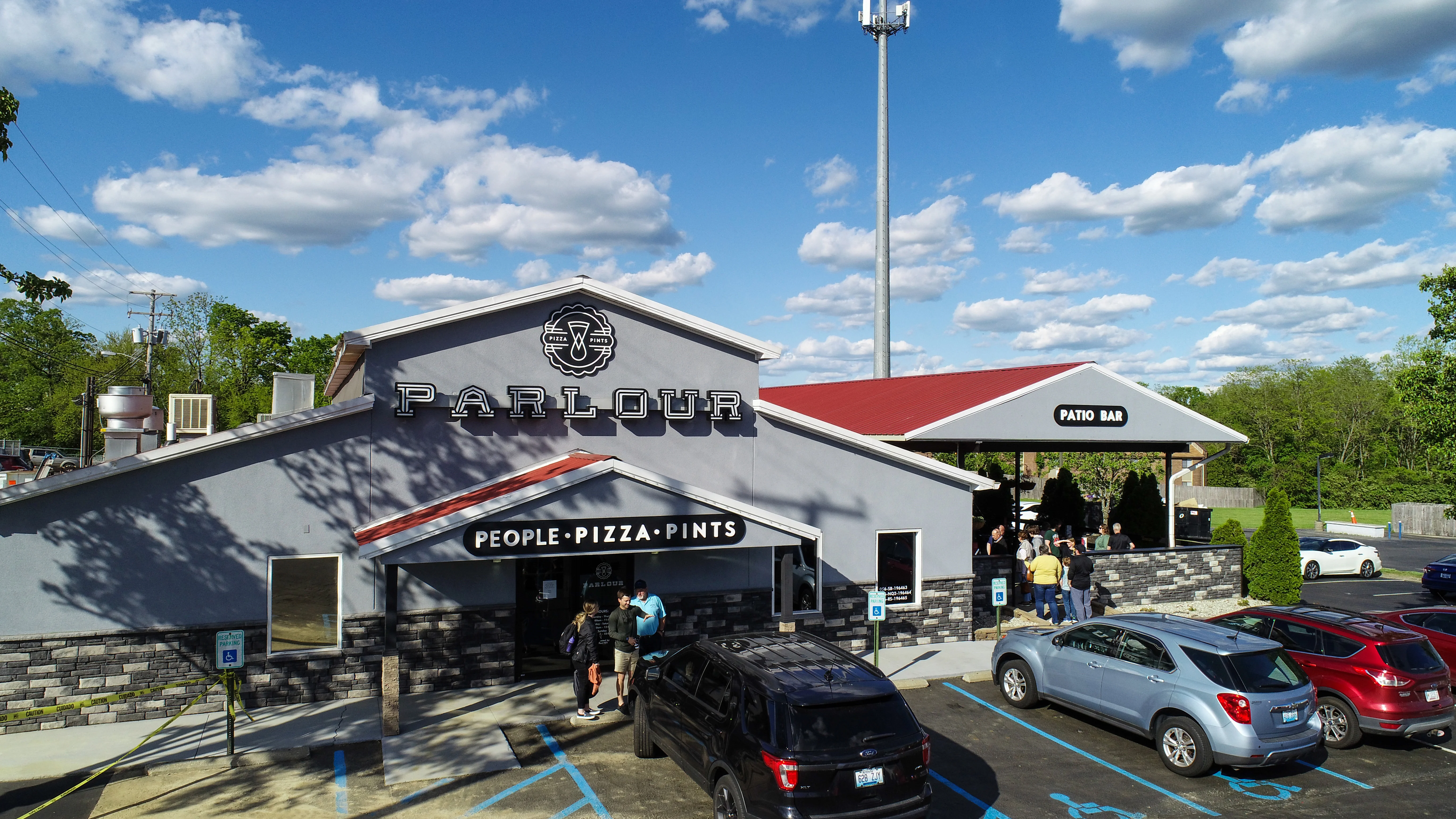 Exterior view of a lively pizza restaurant with a patio bar
