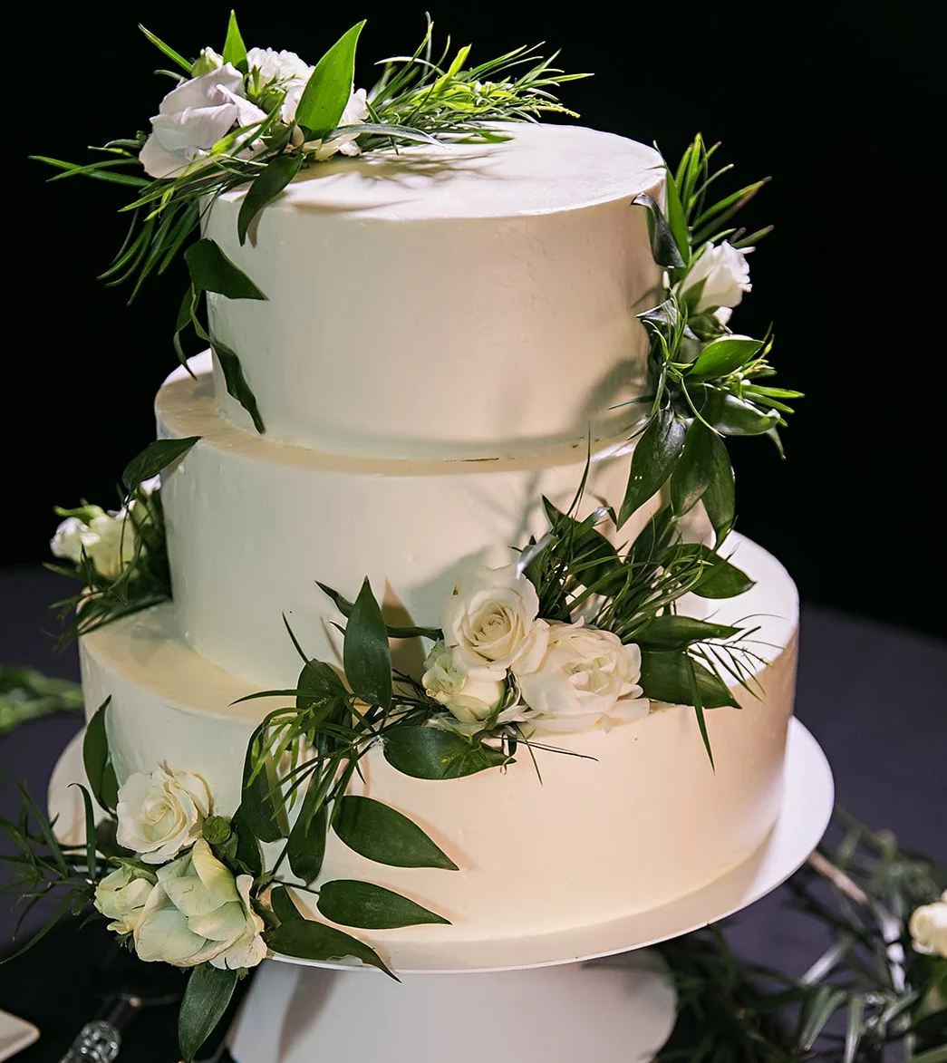 Elegant three-tier wedding cake adorned with fresh flowers
