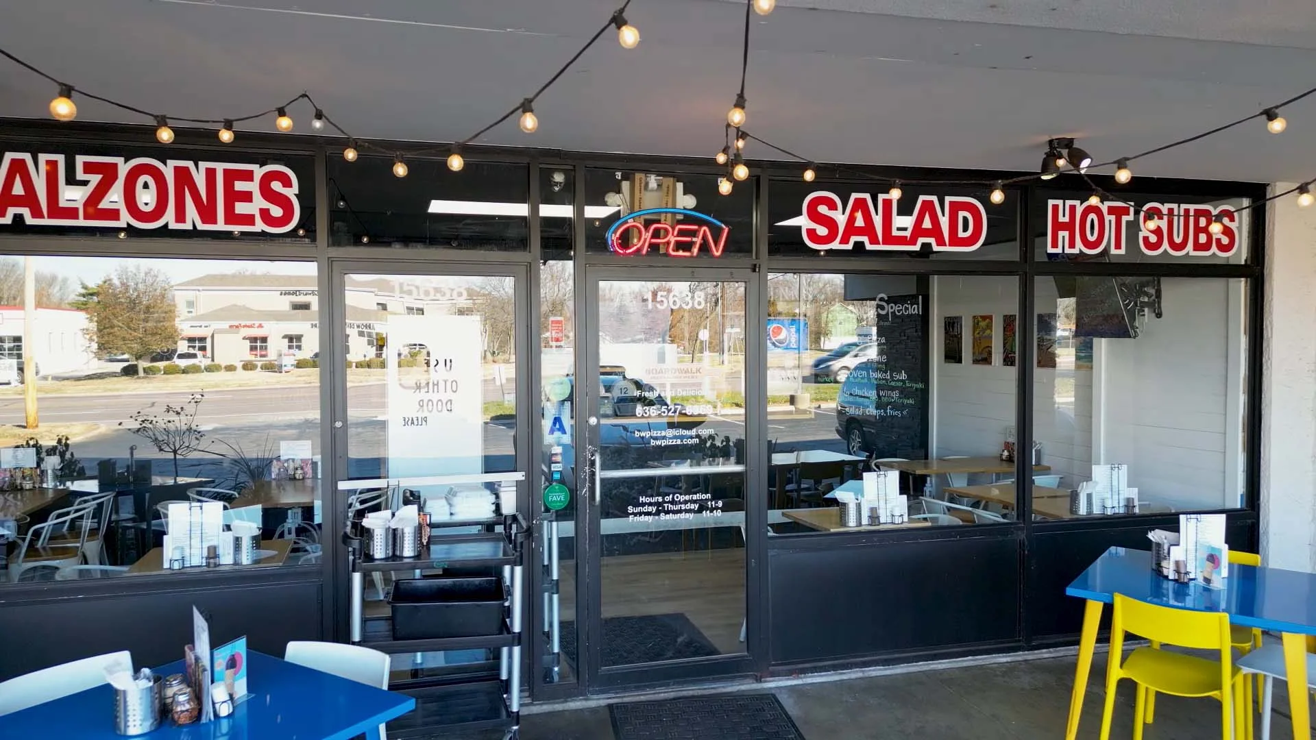 Cozy restaurant entrance with bright signage and outdoor seating