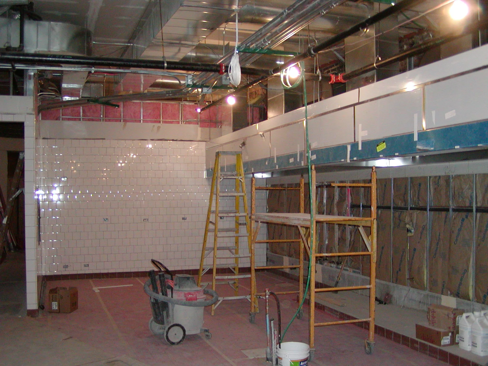 Under-construction restaurant kitchen with tiled walls and scaffolding