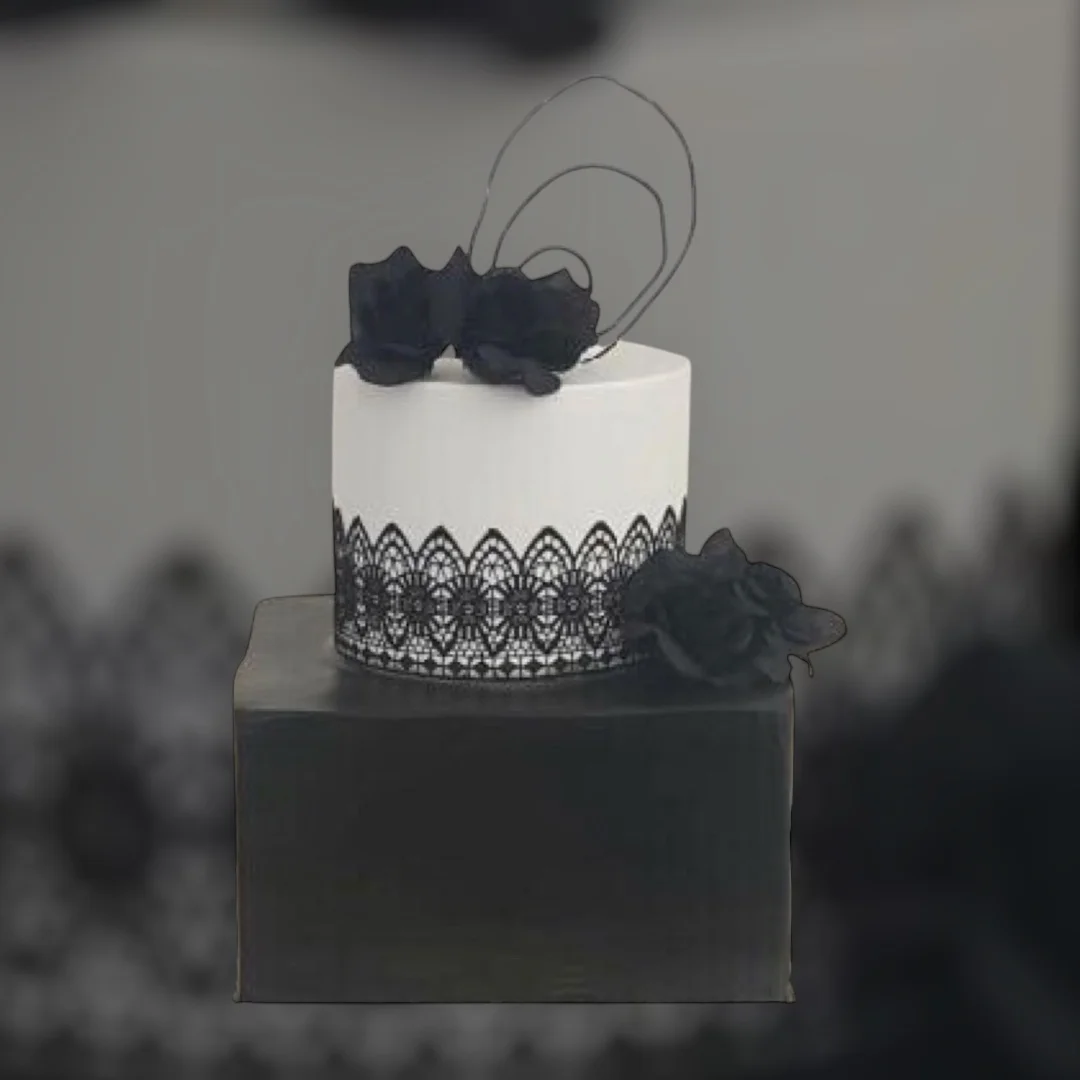 Elegant black and white wedding cake with lace and floral decorations